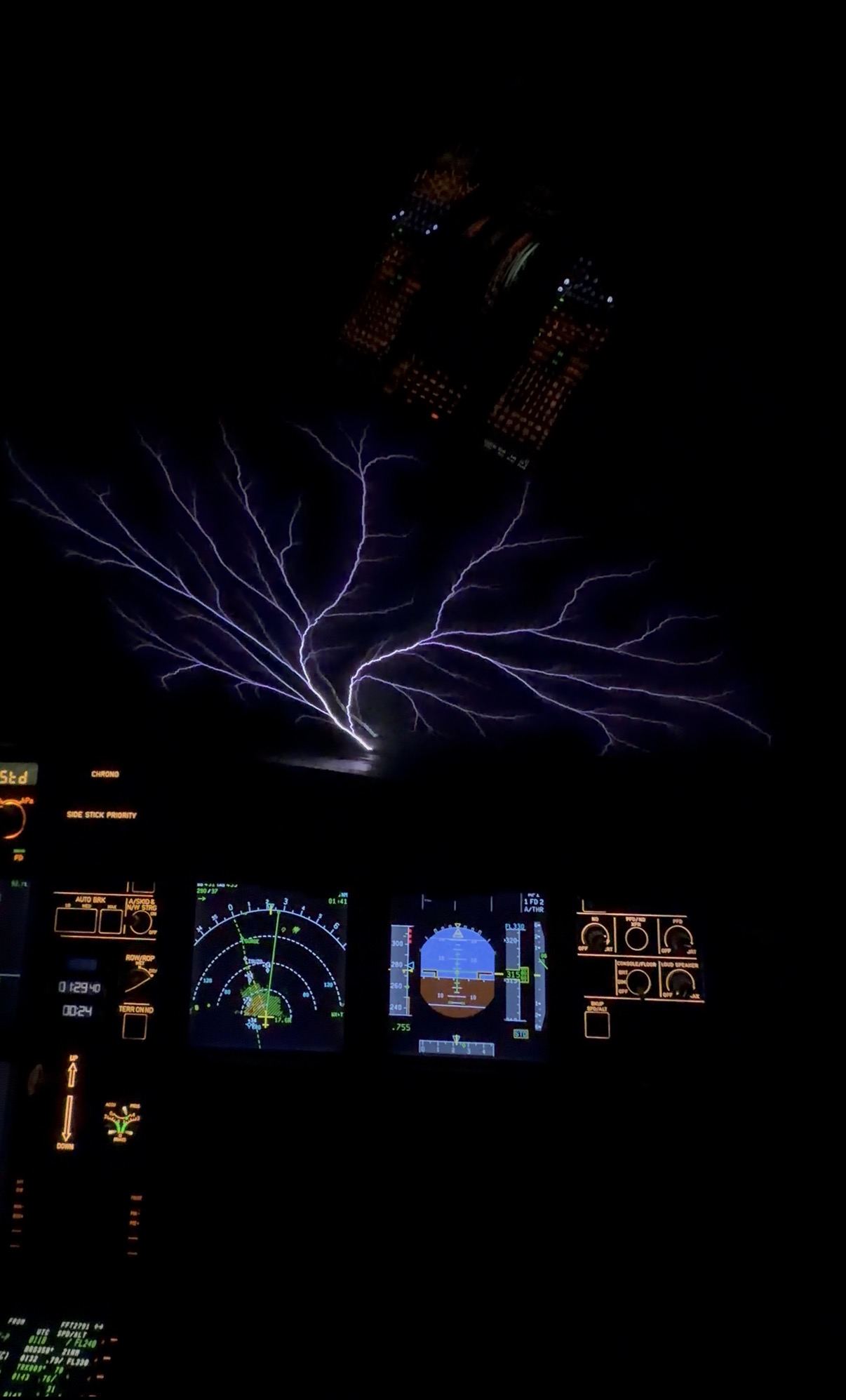 Lightning ahead of the flight deck at night, instruments glowing below