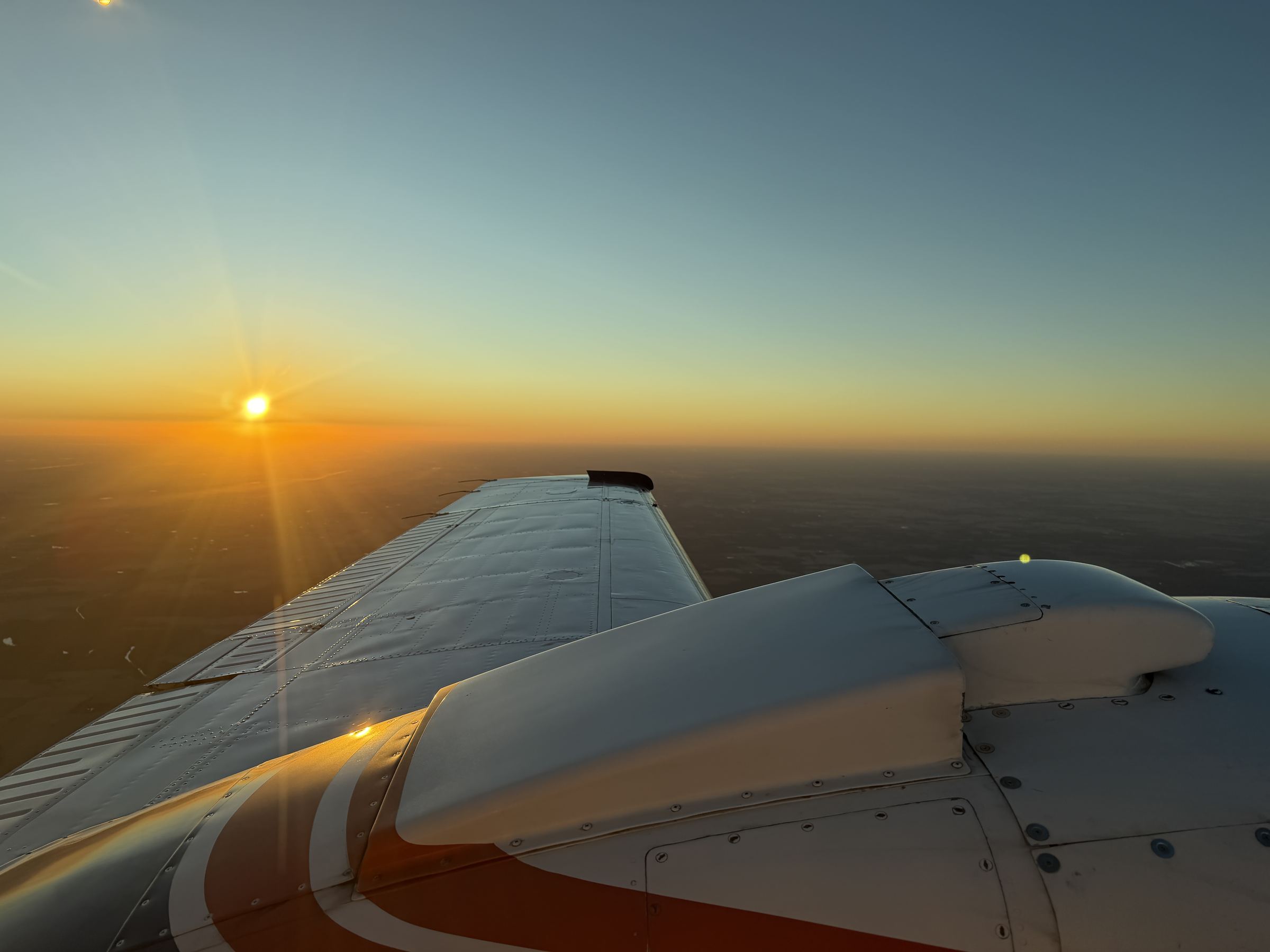 A piston twin's wing pointed into the low sun